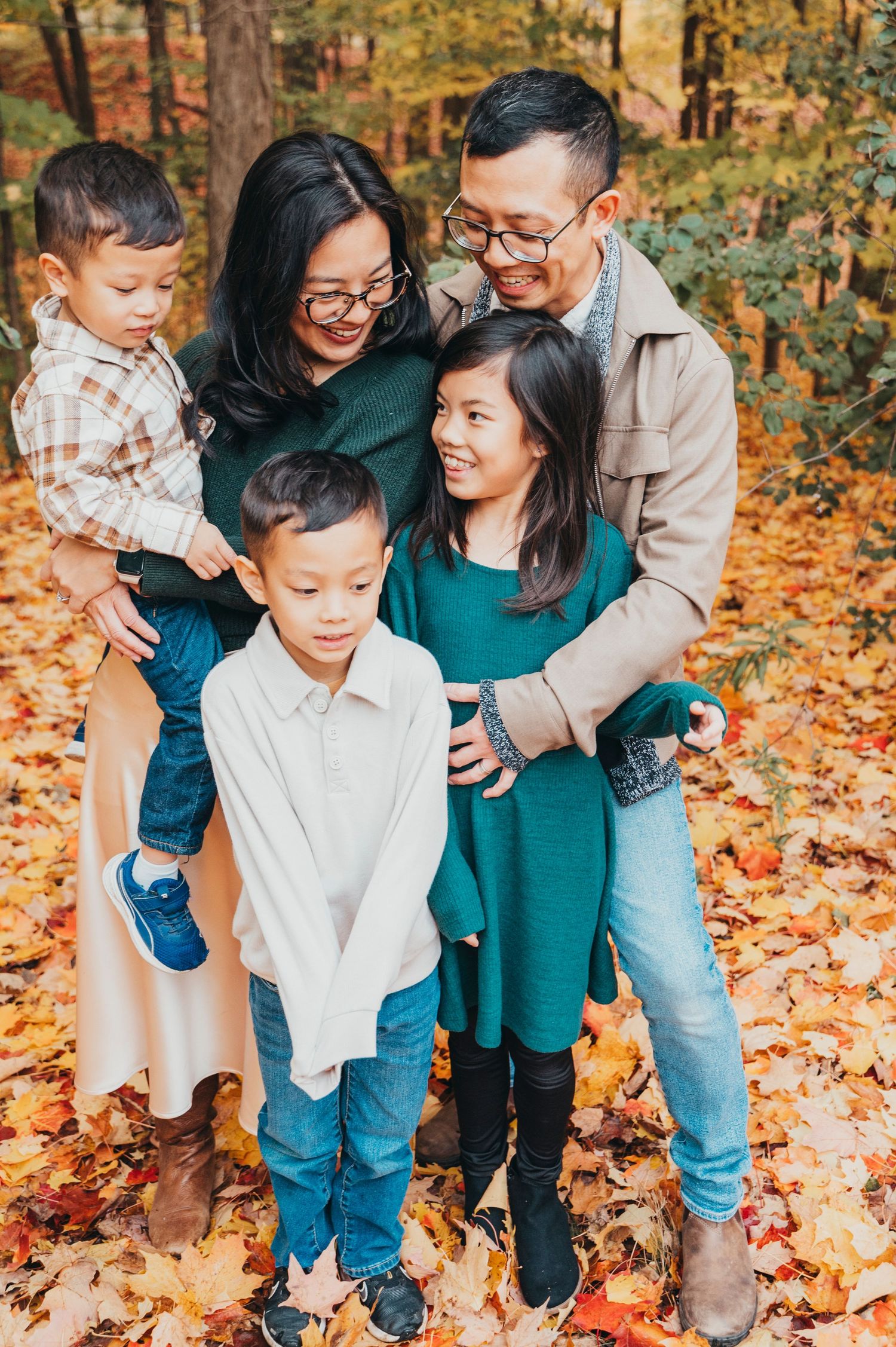 Mississauga photographer captures family hugging and laughing on a bed of leaves for fall photos