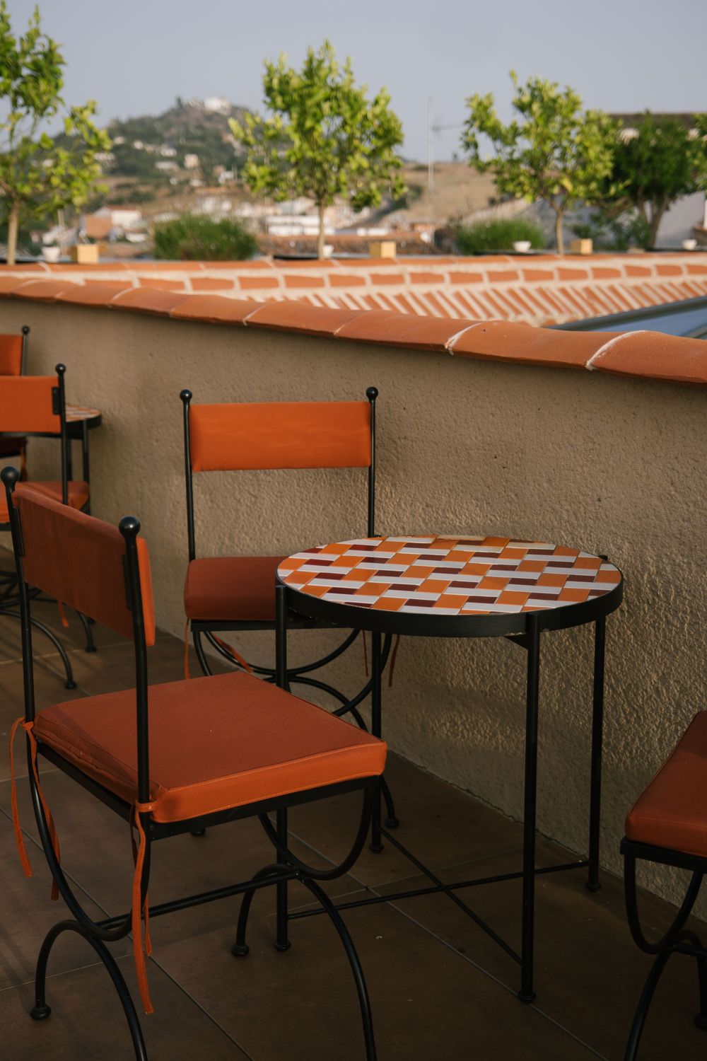 Sunny terrace with mosaic tables and orange chairs in Caceres, Spain