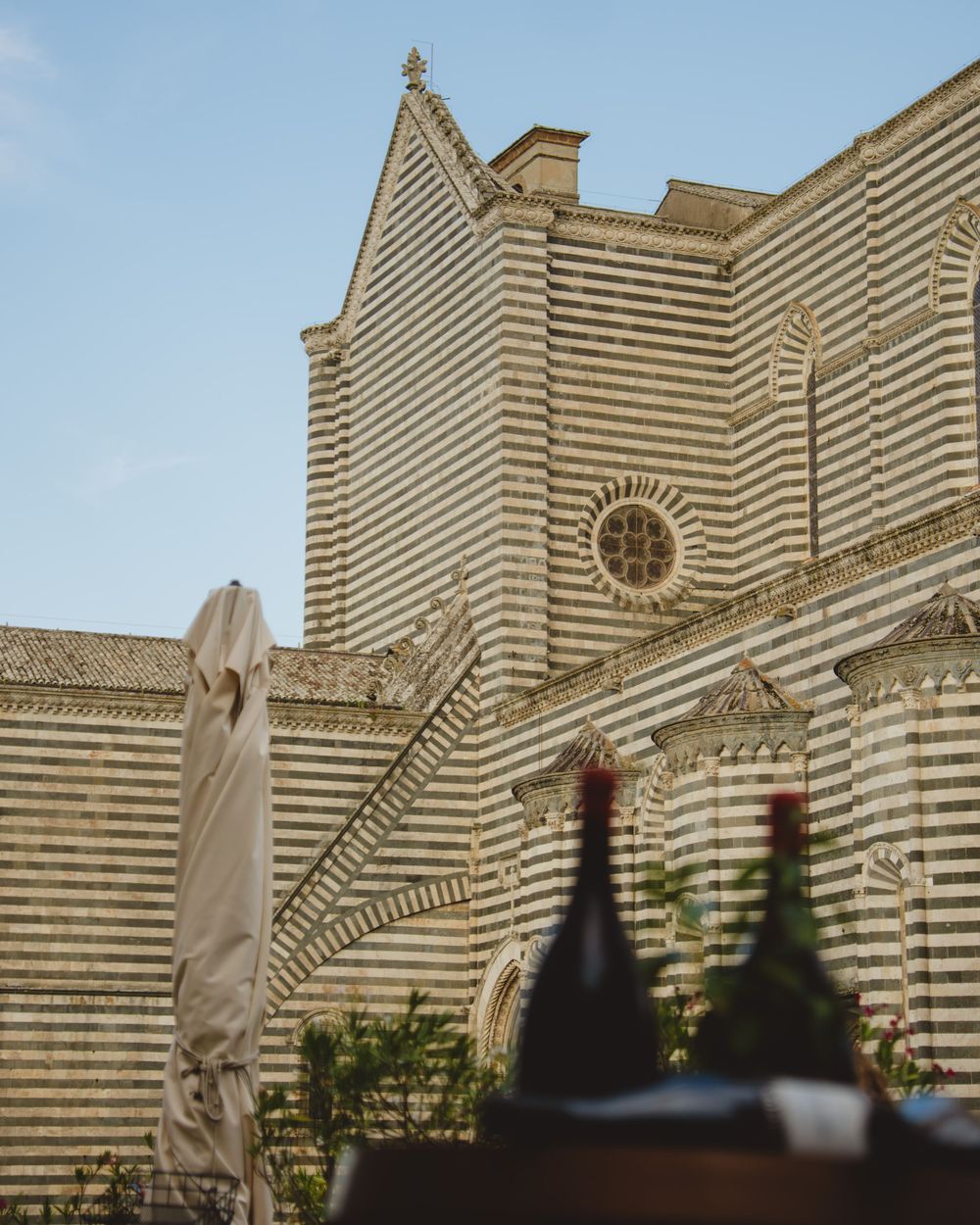 Striped stone facade of a Tuscan cathedral under a blue sky