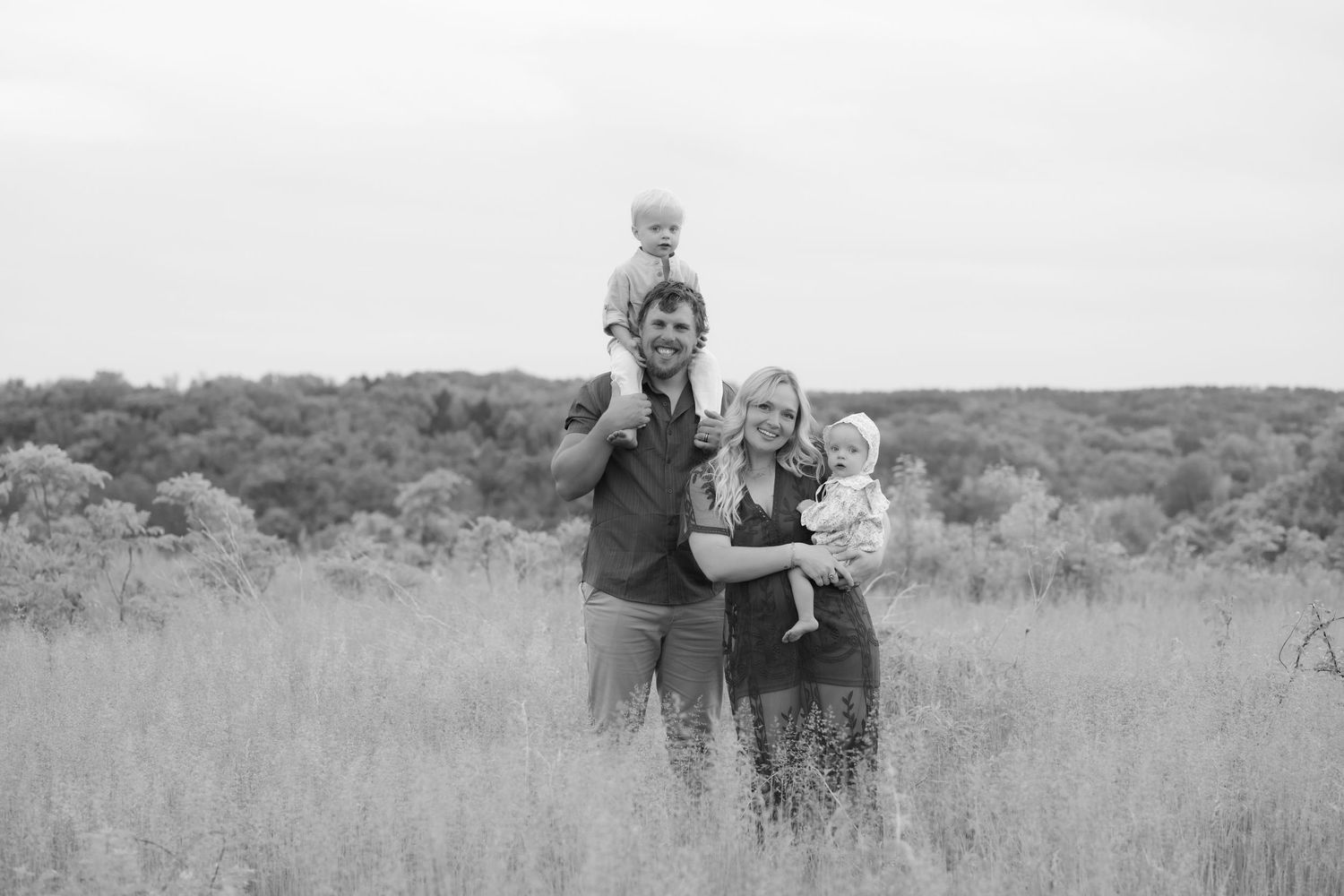 wide expansive black and white image of family in front of rolling hills for a full family photo in Hudson, WI.