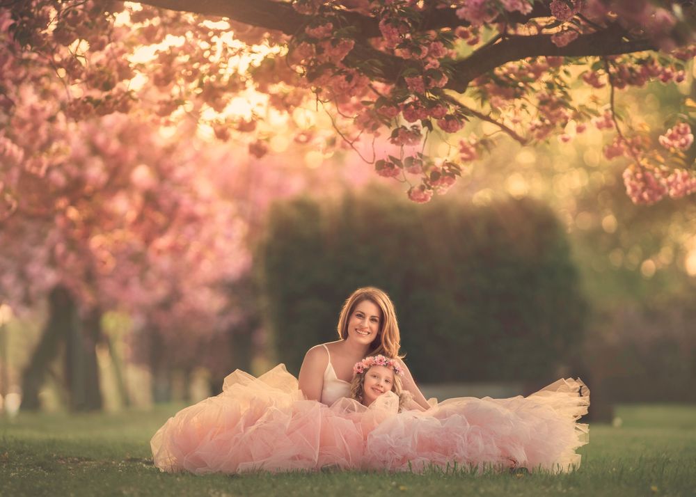 Mother and daughter embracing during a spring Mommy and Me photography session surrounded by cherry blossoms.