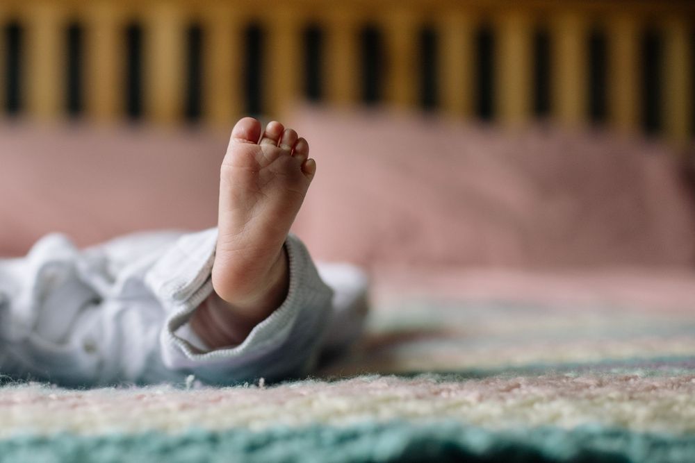 Close-up of tiny newborn baby feet resting on a soft blanket in a crib, perfect for infant and nursery concepts.