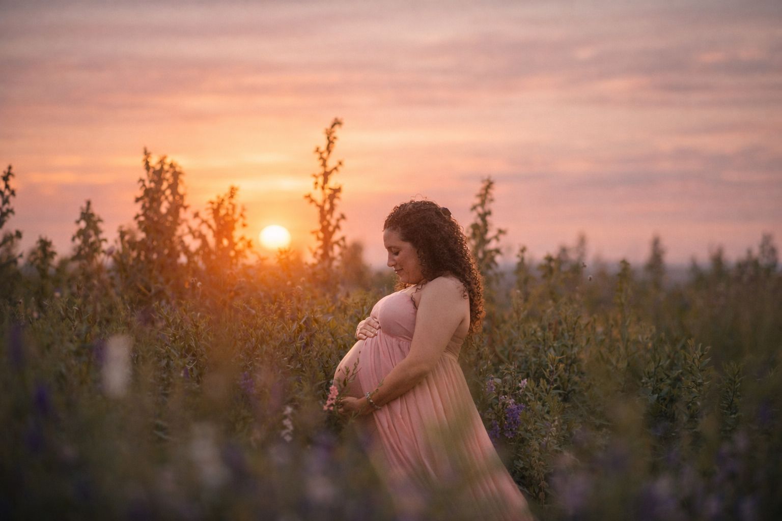 Expectant mother posing among wildflowers during an outdoor maternity photography session.