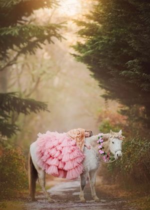 Winter unicorn portrait session featuring a girl in a beautiful dress posing with a unicorn.