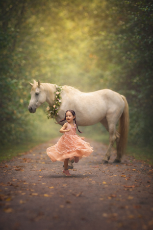 Magical unicorn photography session featuring a child posing with a unicorn for a fine art fantasy portrait.