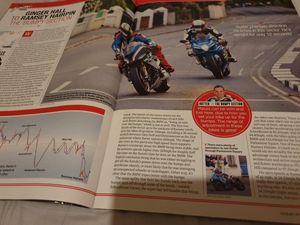 Open magazine spread featuring two superbikes racing on the Isle of Man TT course between Ginger Hall and Ramsey Hairpin.