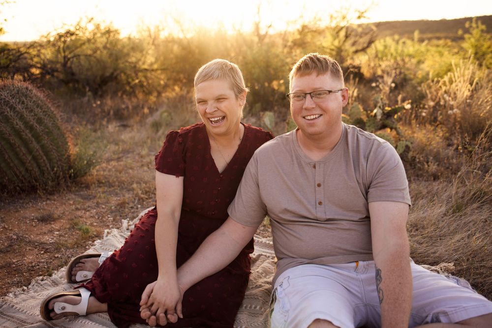 Couple smiling and laughing together outdoors in desert landscape at golden hour sunset.