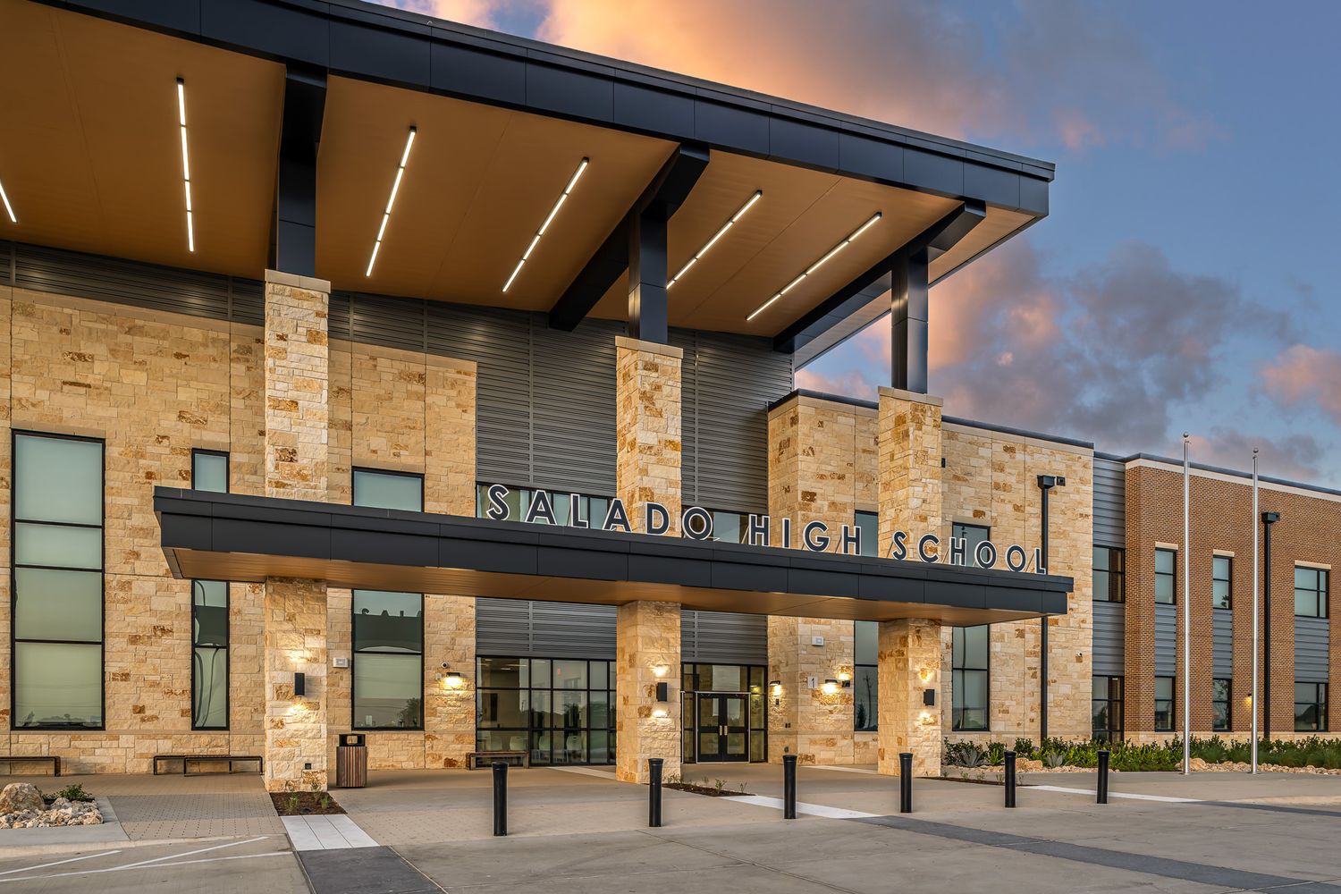 Modern Smuads High School entrance with stone facade and dramatic evening sky.