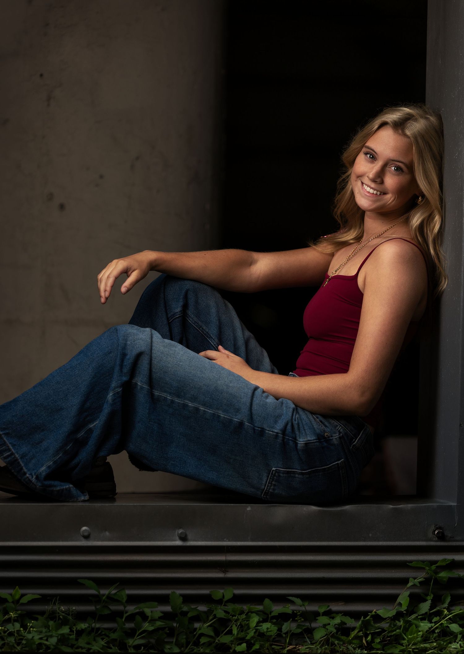 Senior portrait of a blonde girl sitting in an architectural window opening