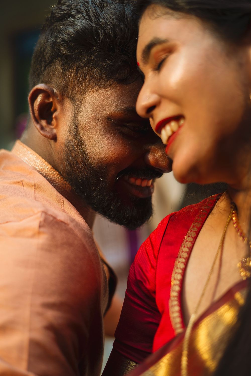 A close-up of a smiling Indian couple in traditional attire sharing an intimate, joyful moment together.