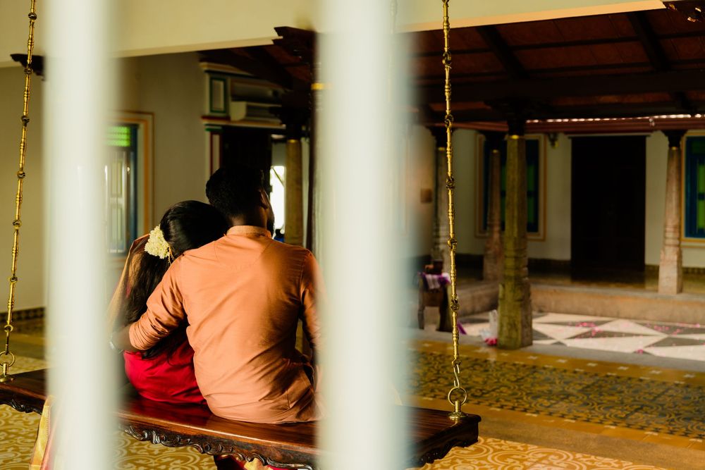 Couple sitting together on a wooden swing in a traditional Indian courtyard setting.