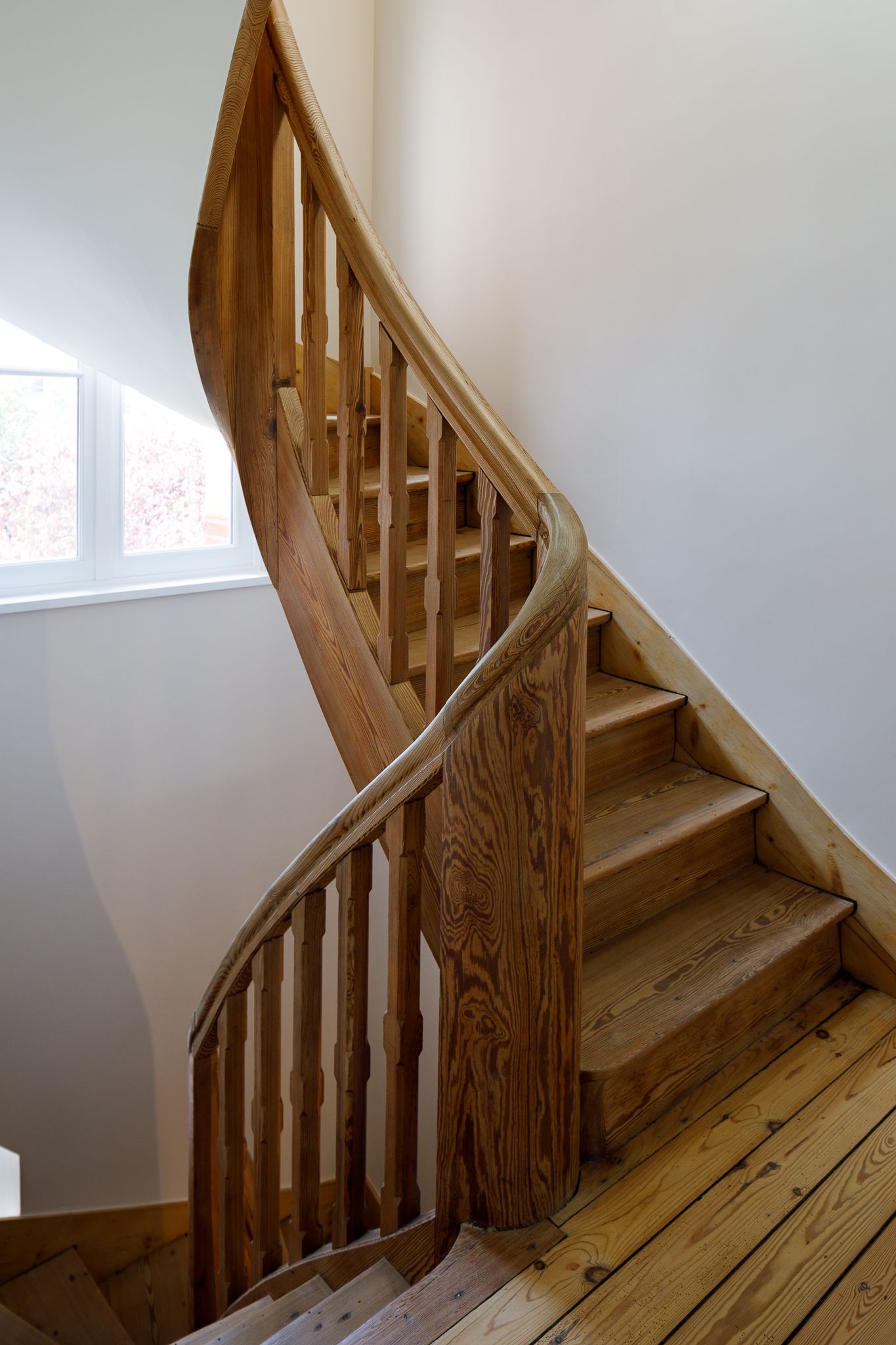 Élégant escalier en bois incurvé avec rampe en chêne naturel et parquets en bois.