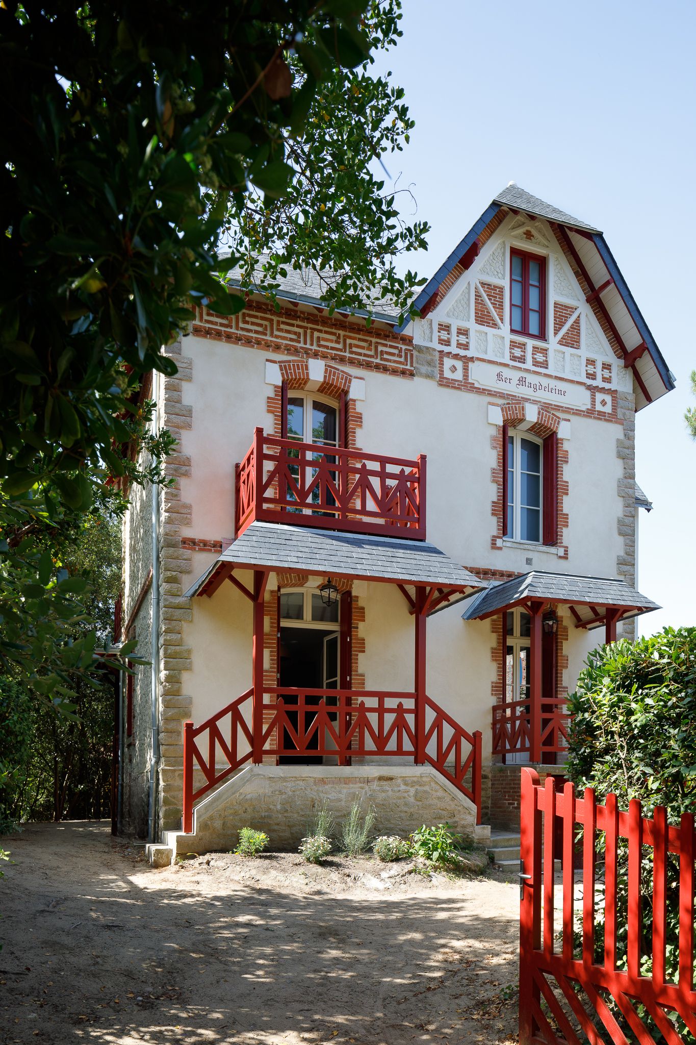 Charmante villa française d'époque baptisée Ker Magdeleine, dotée de balcons rouges, d'une façade décorative et d'un portail de jardin rouge