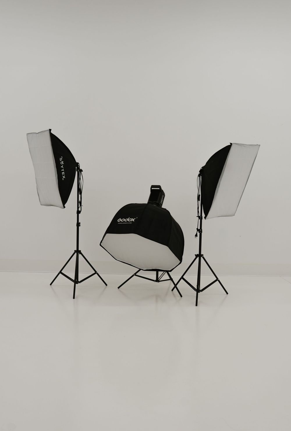 Godox three-light studio photography kit with two softboxes on stands and one octagon softbox on floor.