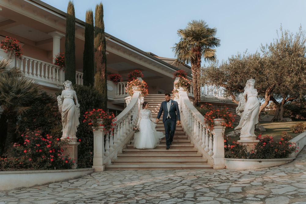 Gli sposi camminano accanto a una scalinata monumentale nel giardino.