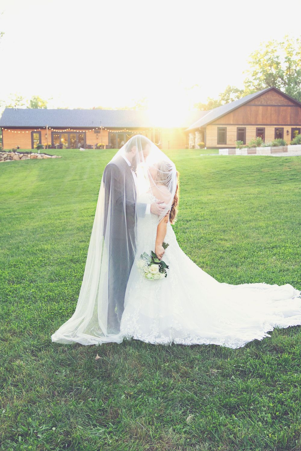 Romantic back-lit under-the-veil portrait by a Southwest Michigan photo and video team at  sunset on Augusta Creek Events lawn.