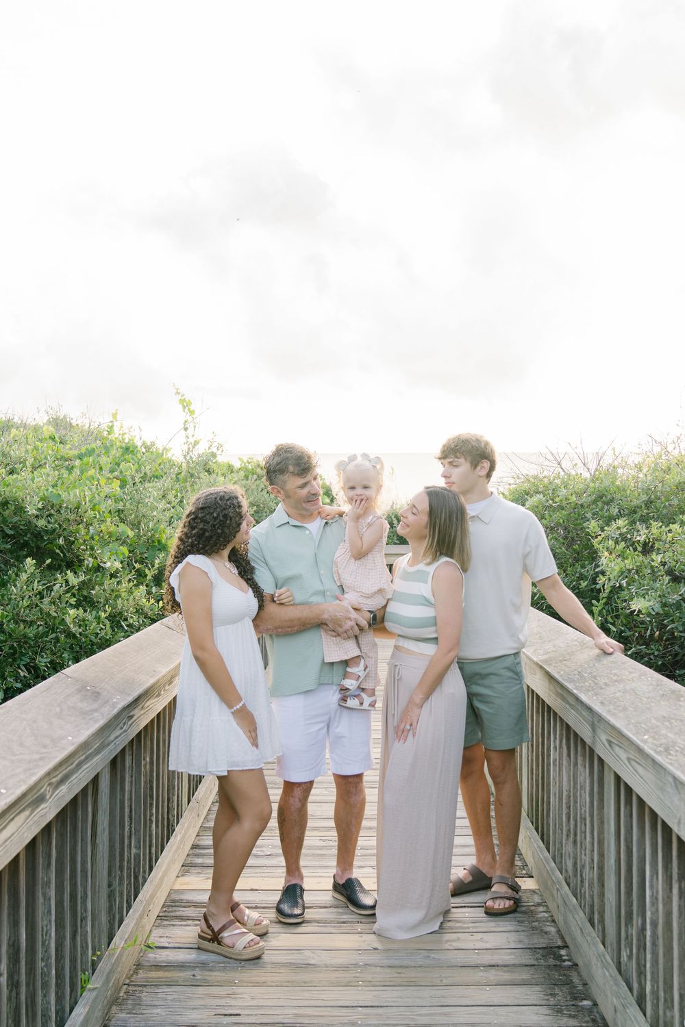 Family gathered on a beach boardwalk during their Jekyll Island vacation photo session with Lindy Rebro & Traci Soles