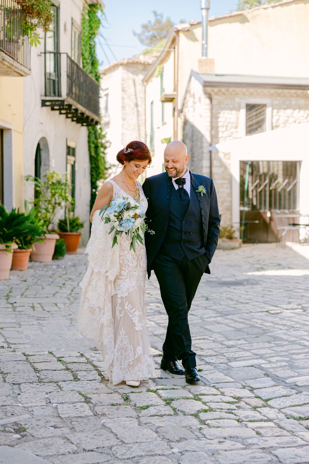 Cosimo e Tanya camminano lungo una strada lastricata del borgo.