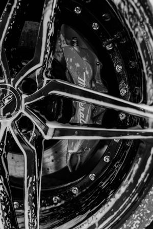 Black and white close-up of a luxury car wheel with a Brembo brake caliper and stylish multi-spoke alloy rim.
