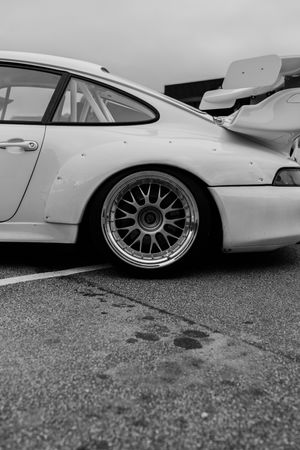 Black and white photo of a lowered Porsche 911 GT3 race car with BBS wheels and large rear wing on track.