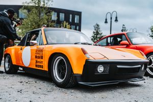 Orange Porsche 914 race car with wide body kit and racing livery displayed at an outdoor car show.