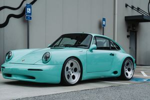 Mint green Porsche 911 classic sports car parked in a lot, featuring wide body kit and silver alloy wheels.