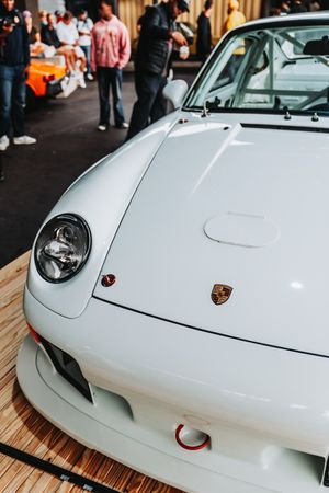 White Porsche 993 911 front end detail with badge at indoor car show event.