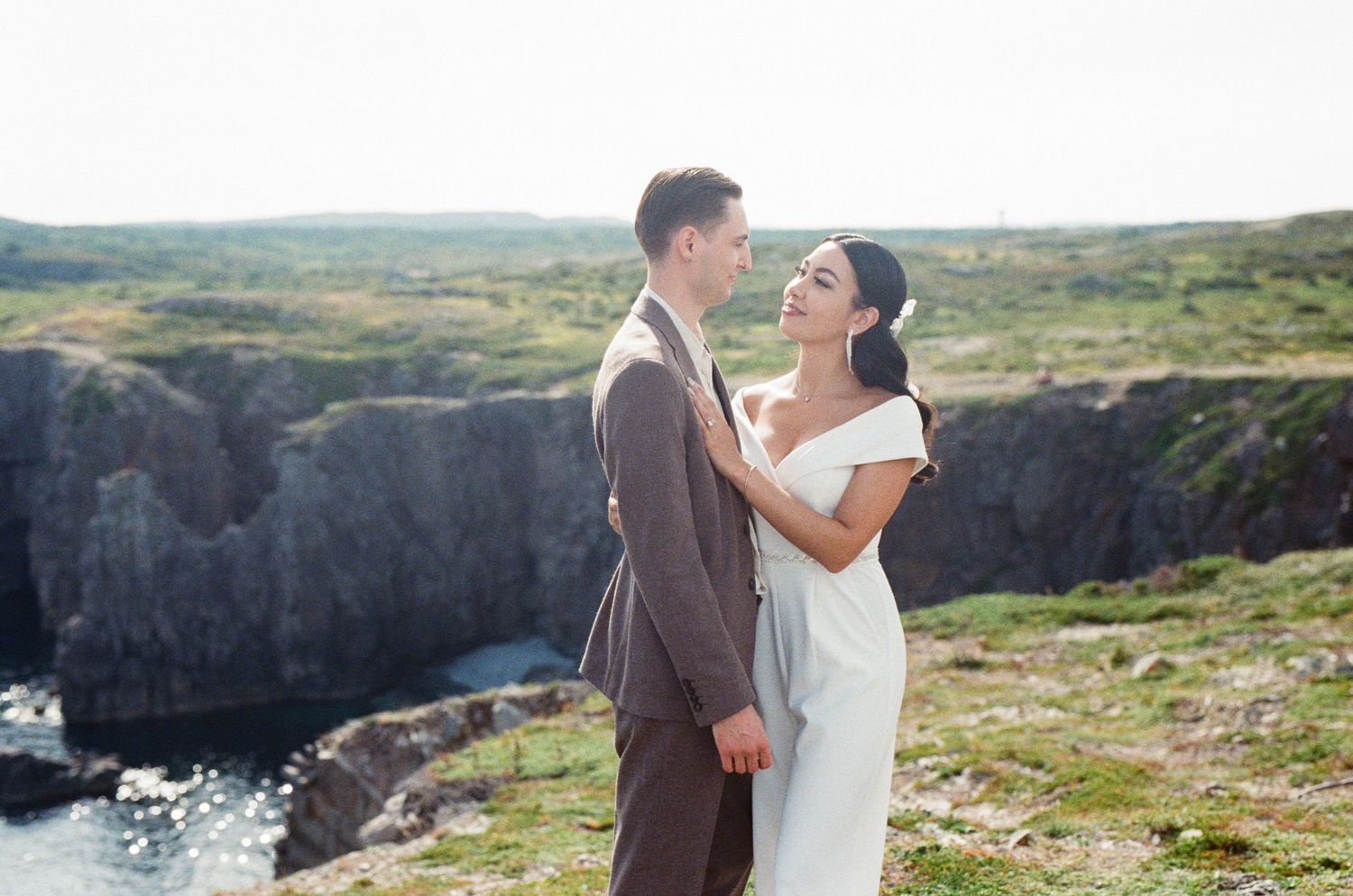 35 mm film photo of bride and groom holding each other on a green hill by the coast on vancouver island