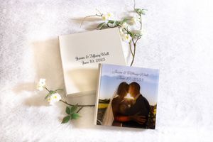 Personalized wedding photo album and square photo book with couple silhouette, decorated with white flowers on soft white background.