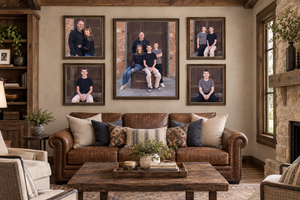 Cozy living room with leather sofa and five framed family portrait photos arranged on a rustic stone wall.