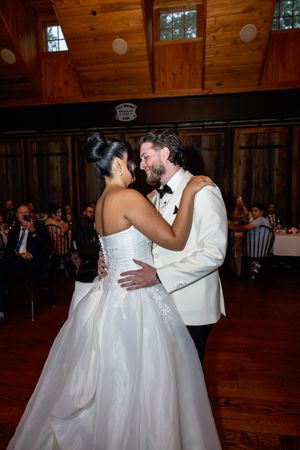 Bride and groom share first dance in rustic wood-paneled wedding reception venue.