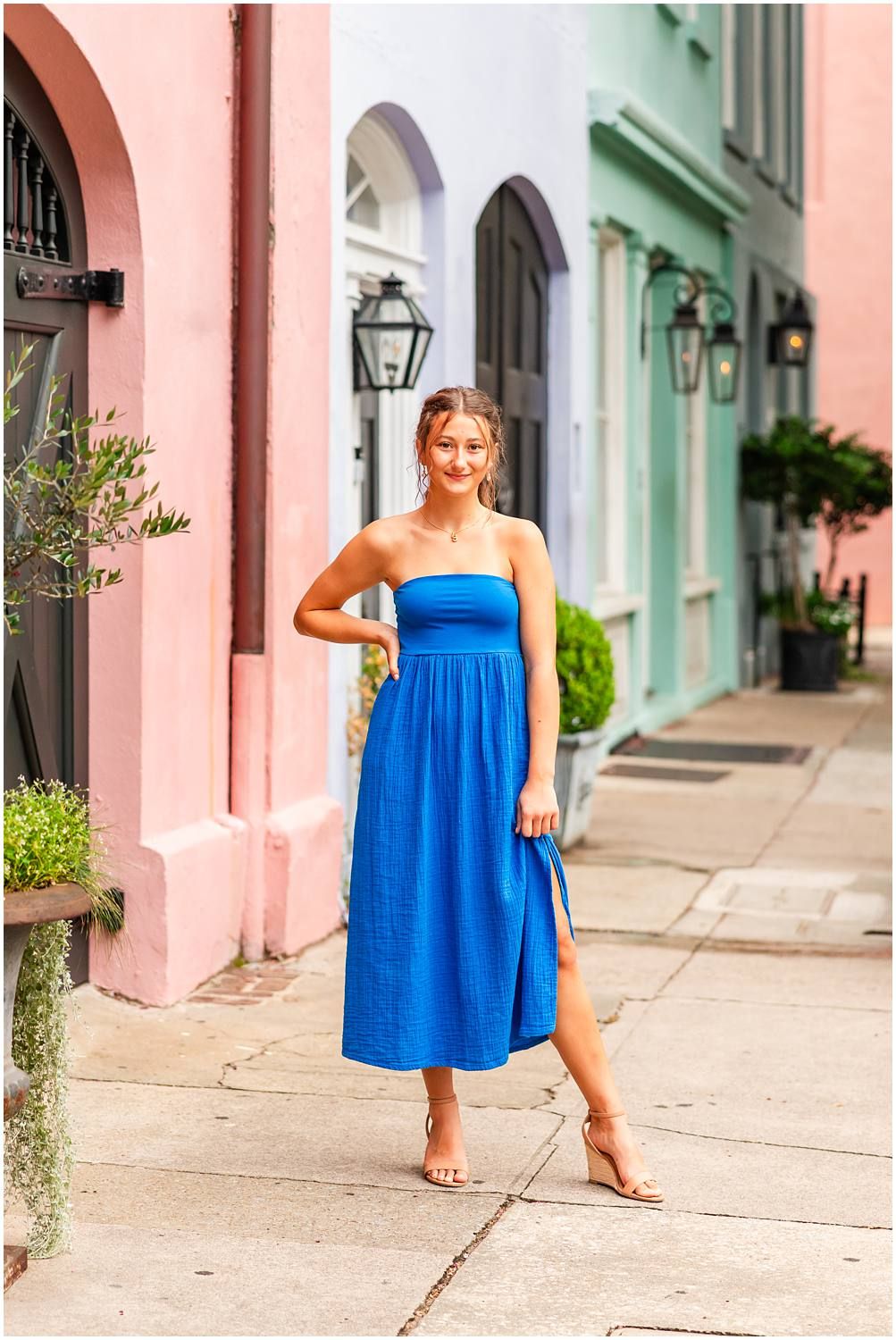 Woman in blue strapless midi dress posing on colorful Rainbow Row street in Charleston, SC.