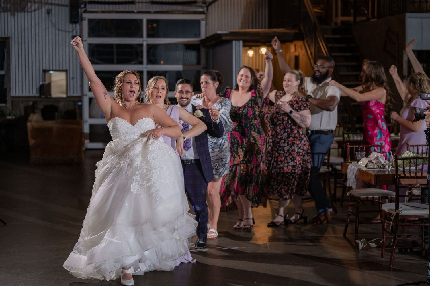 Bride leading guests in a dance on the reception floor inside the Blue Barn at Rockin' H Ranch in Palm City, FL