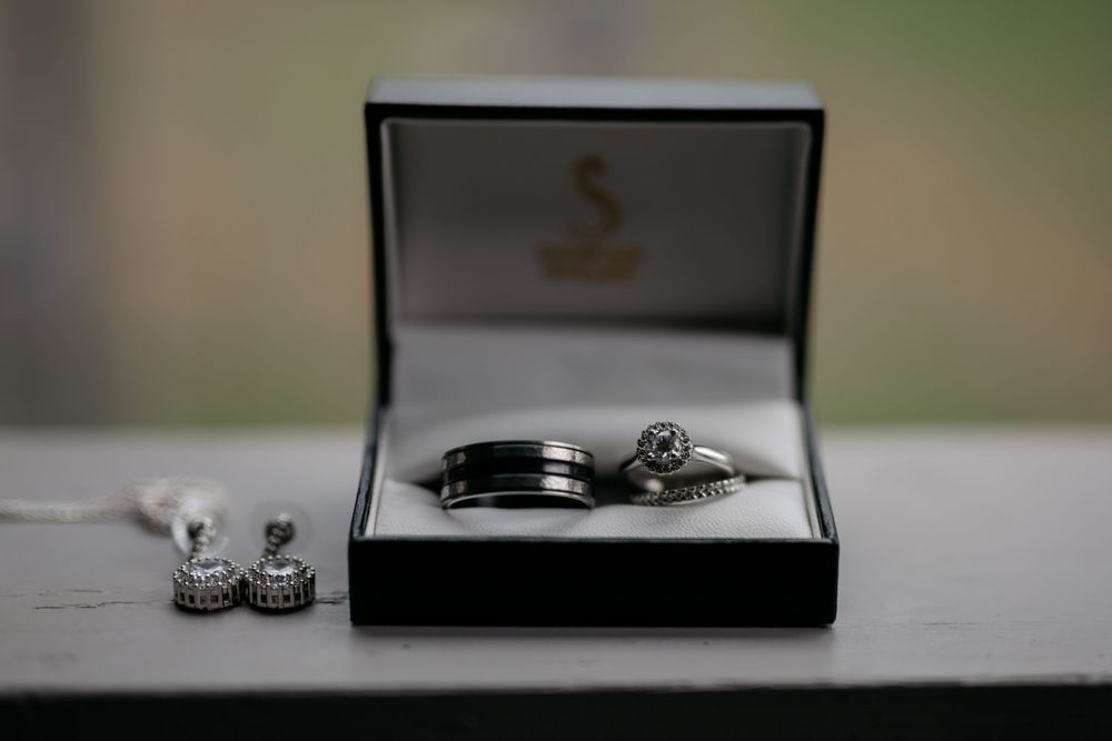 Wedding rings and earrings displayed in an elegant black jewelry box.