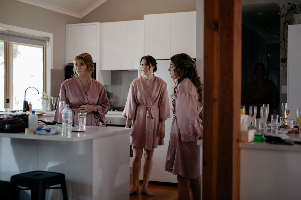 Three people in matching pink robes standing in a modern kitchen.