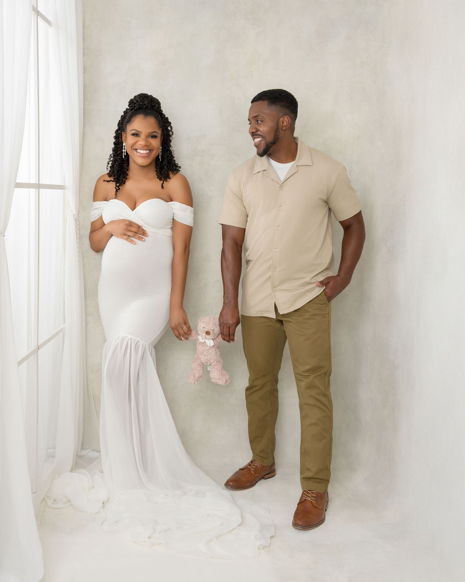 Elegant maternity portrait of an expecting couple in a natural light studio by a Tampa Bay maternity photographer.