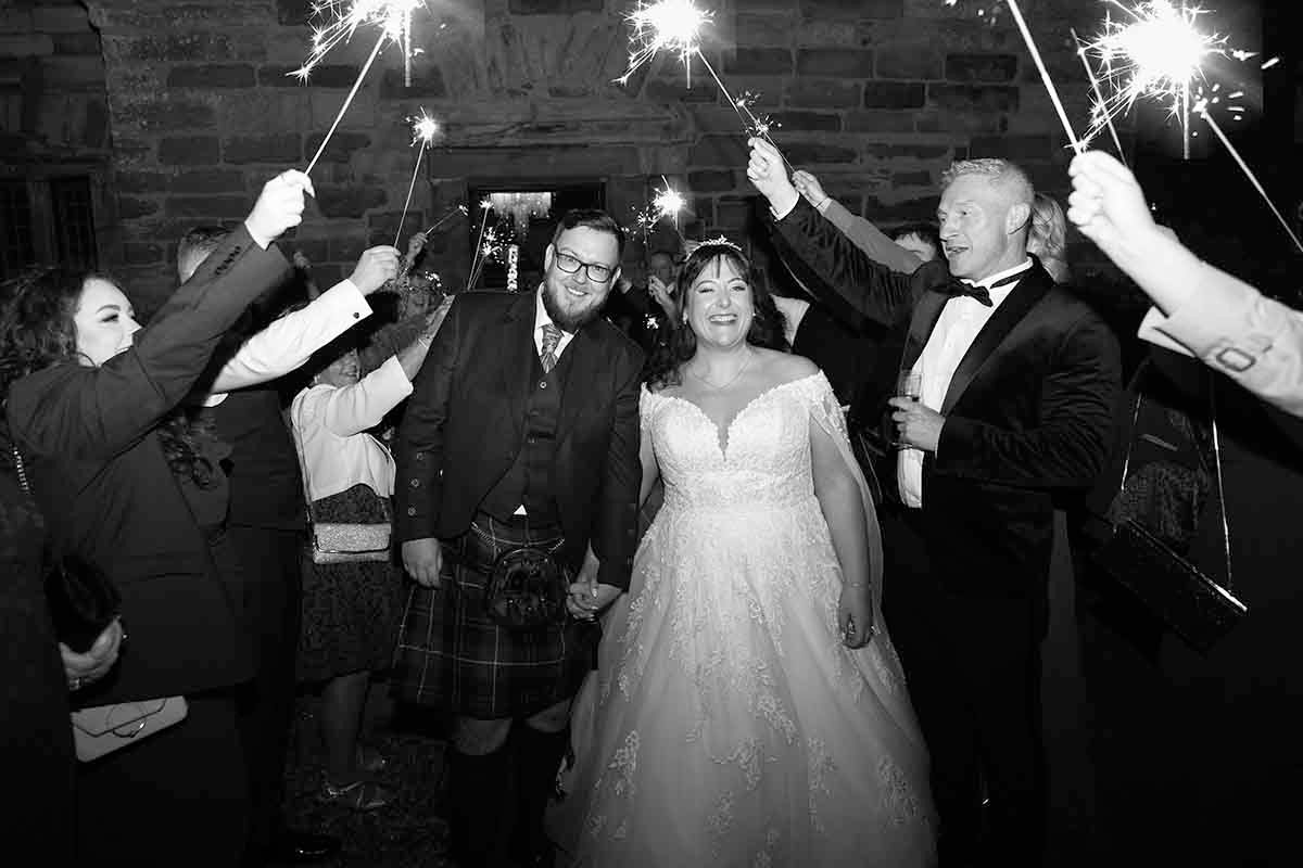 bride and groom receive a guard of honour from guests using sparklers at Dalston Hall , cumbria.