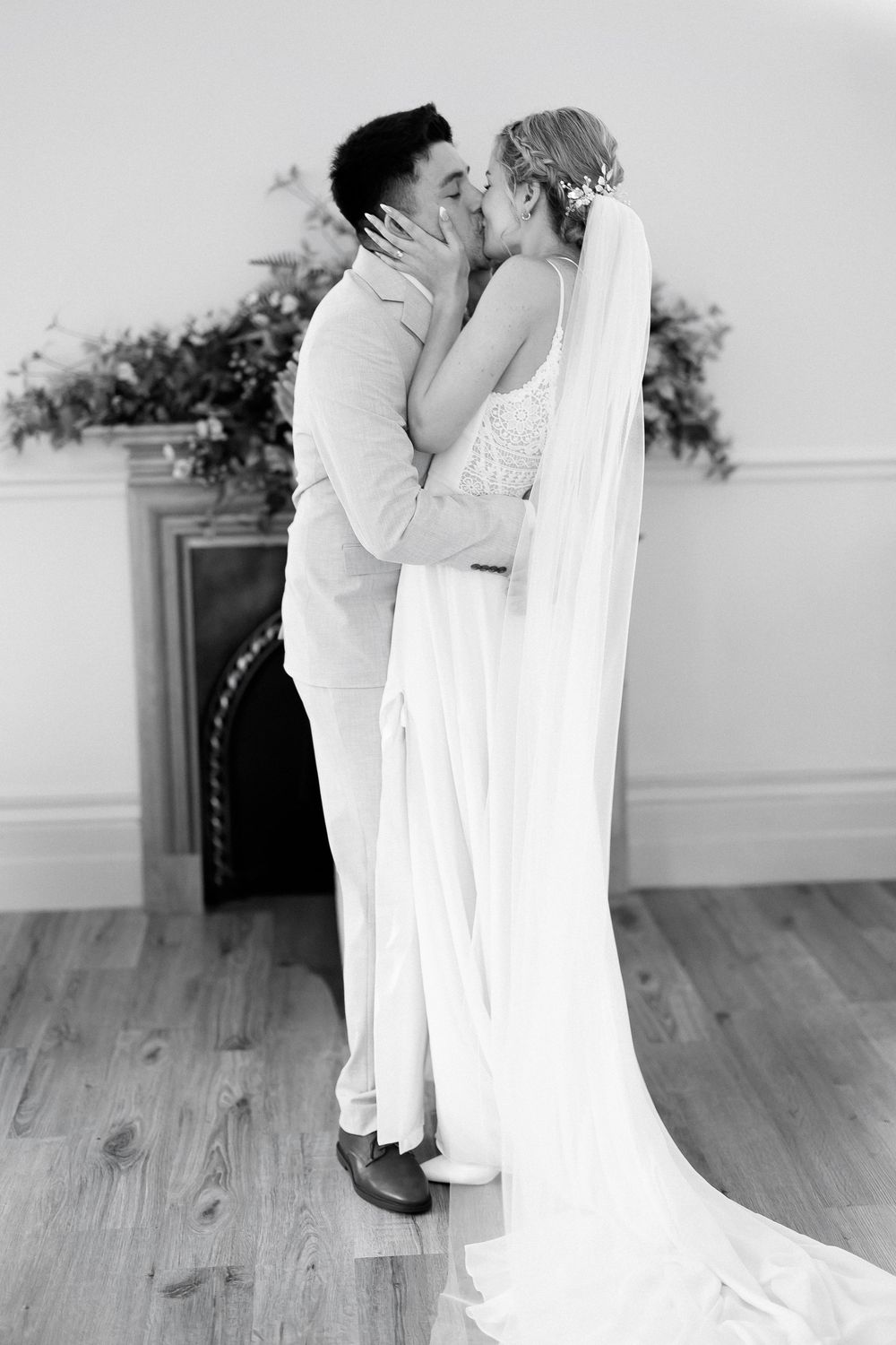 Black and white photo of a bride and groom sharing their first kiss at the altar on their wedding day.