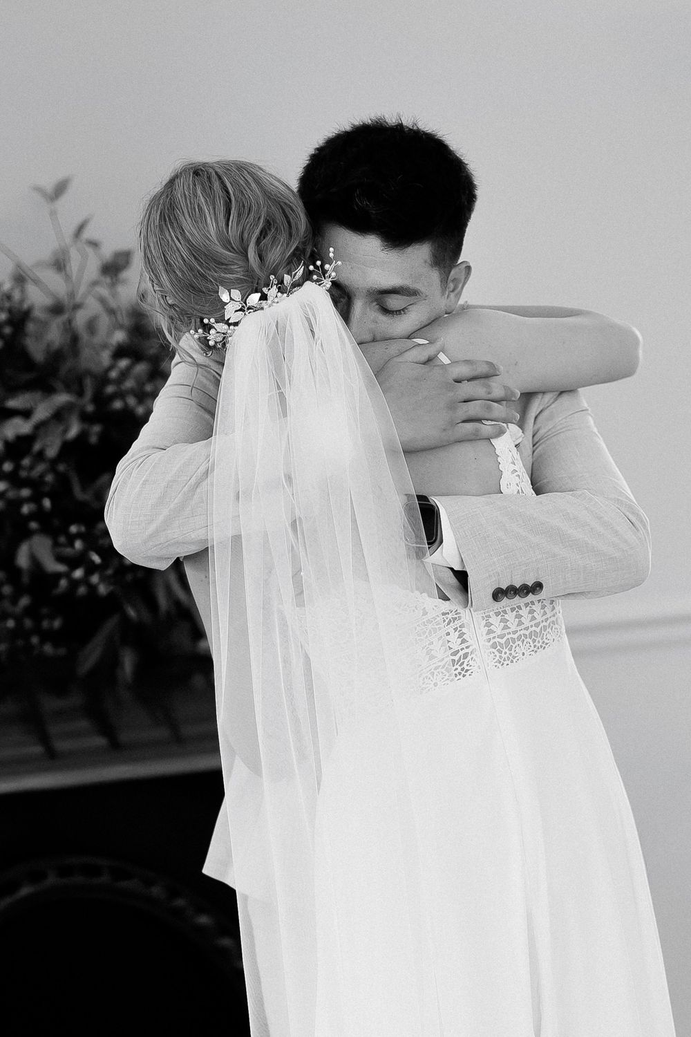 Black and white photo of a bride and groom sharing an emotional embrace on their wedding day.