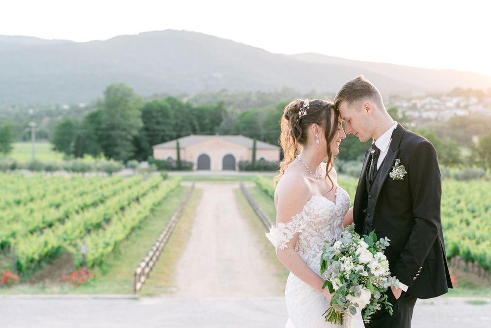 Couple embraces on a scenic overlook with ocean and coastline views during golden hour at their outdoor wedding.