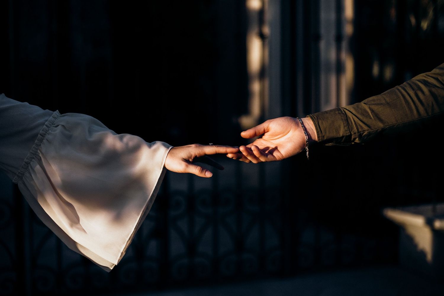 Two hands reaching toward each other in dramatic lighting, creating a mystical atmosphere.