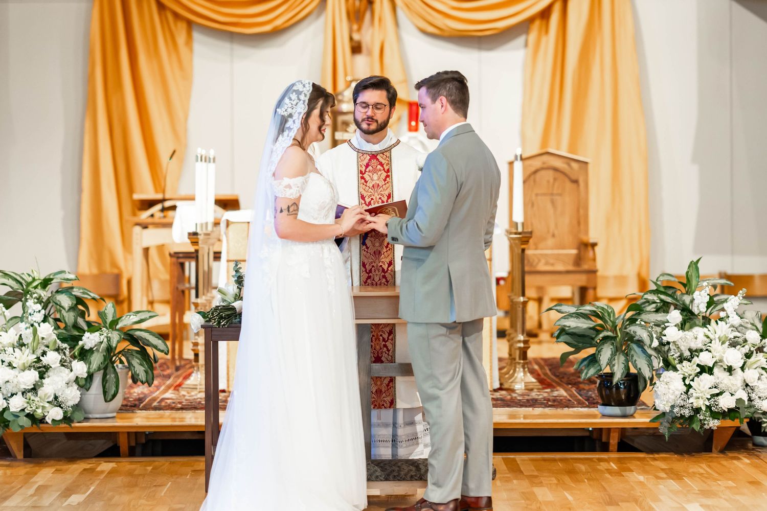 bride and groom exchanging rings at christ the king Catholic Church in baton rouge