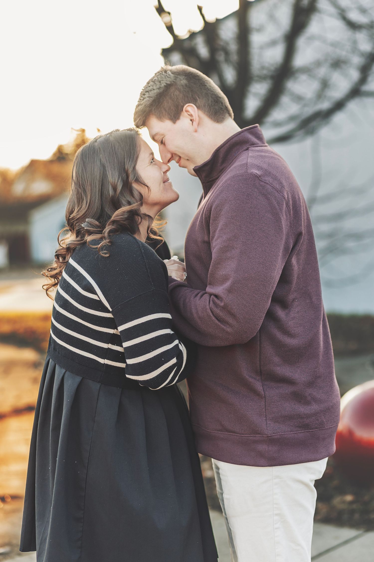 Couple sharing a romantic moment at golden hour, holding hands with an engagement ring visible.