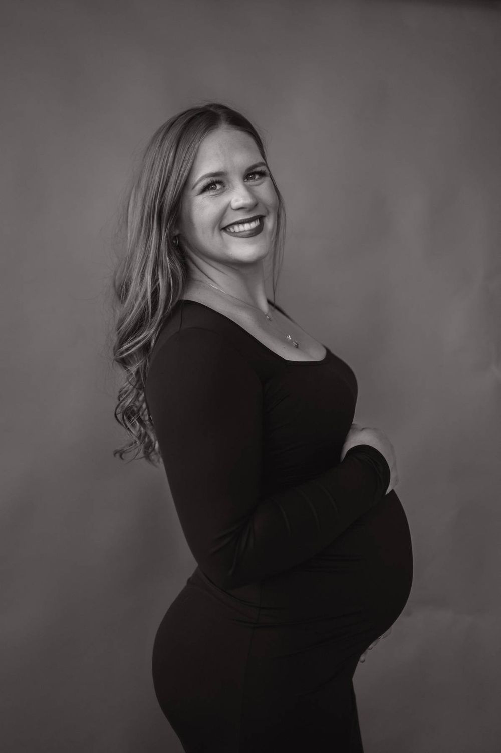 Black and white side profile maternity portrait of smiling pregnant woman in black dress Asheboro NC