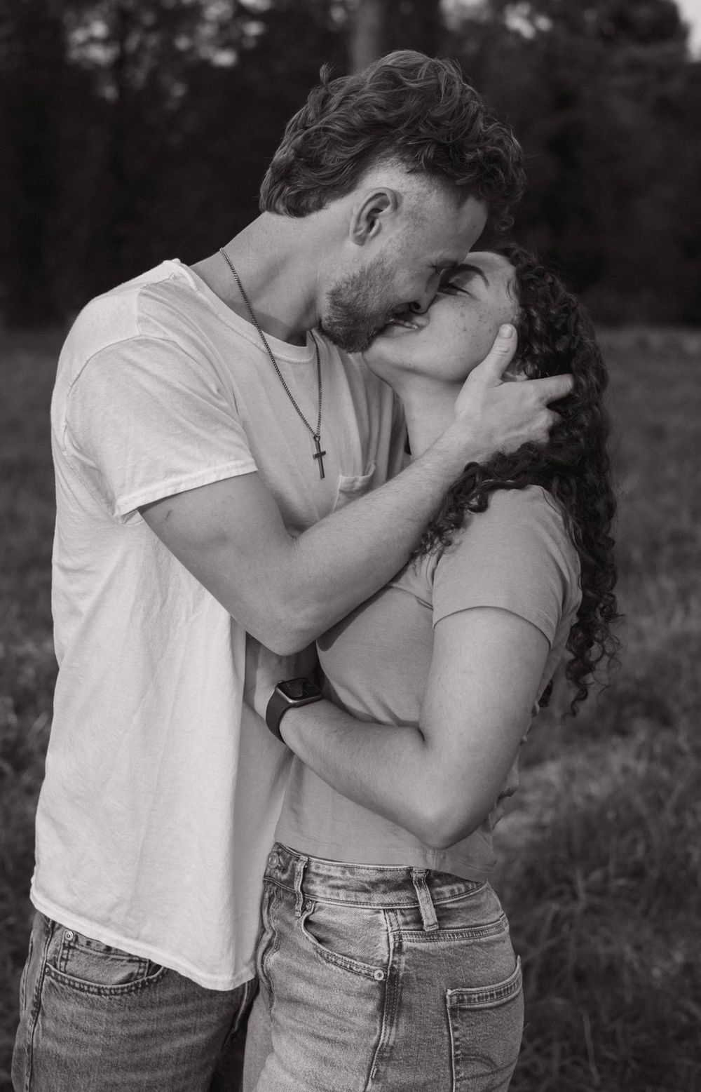 Black and white photo of a passionate couple sharing a kiss in an outdoor field setting, romantic couples photographer Asheboro NC