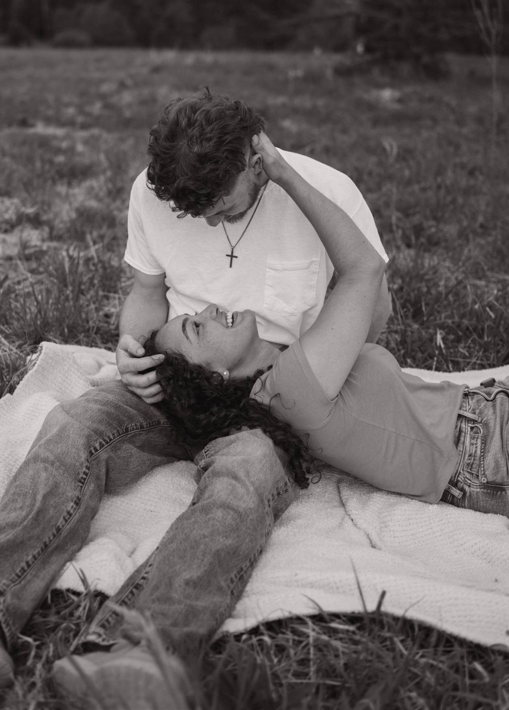 Black and white romantic photo of couple lying on a blanket in a grassy field together Asheboro NC