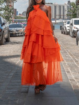 Elegant orange layered chiffon halter gown with ruffled tiers worn on a sunny city street.