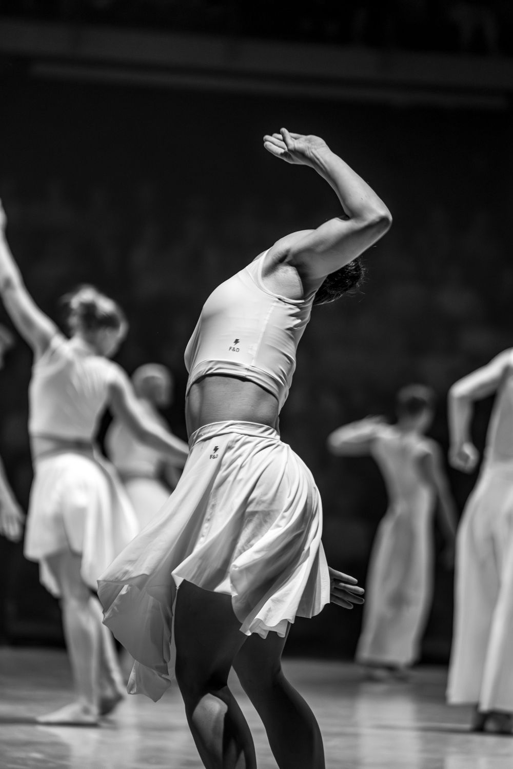 Black and white photo of female dancers in white skirts performing on stage.