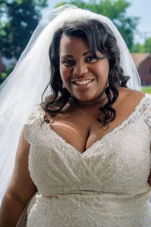 A radiant bride wearing a white lace wedding dress and veil poses for a portrait.