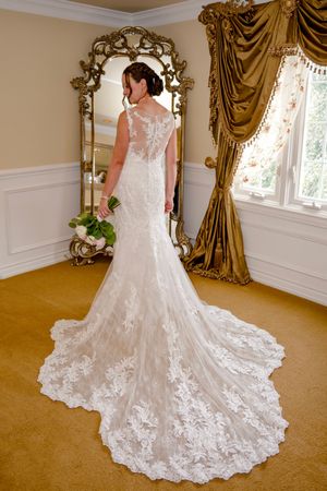 Beautiful lace wedding dress with intricate floral details and dramatic train shown from multiple angles on carpeted floor.